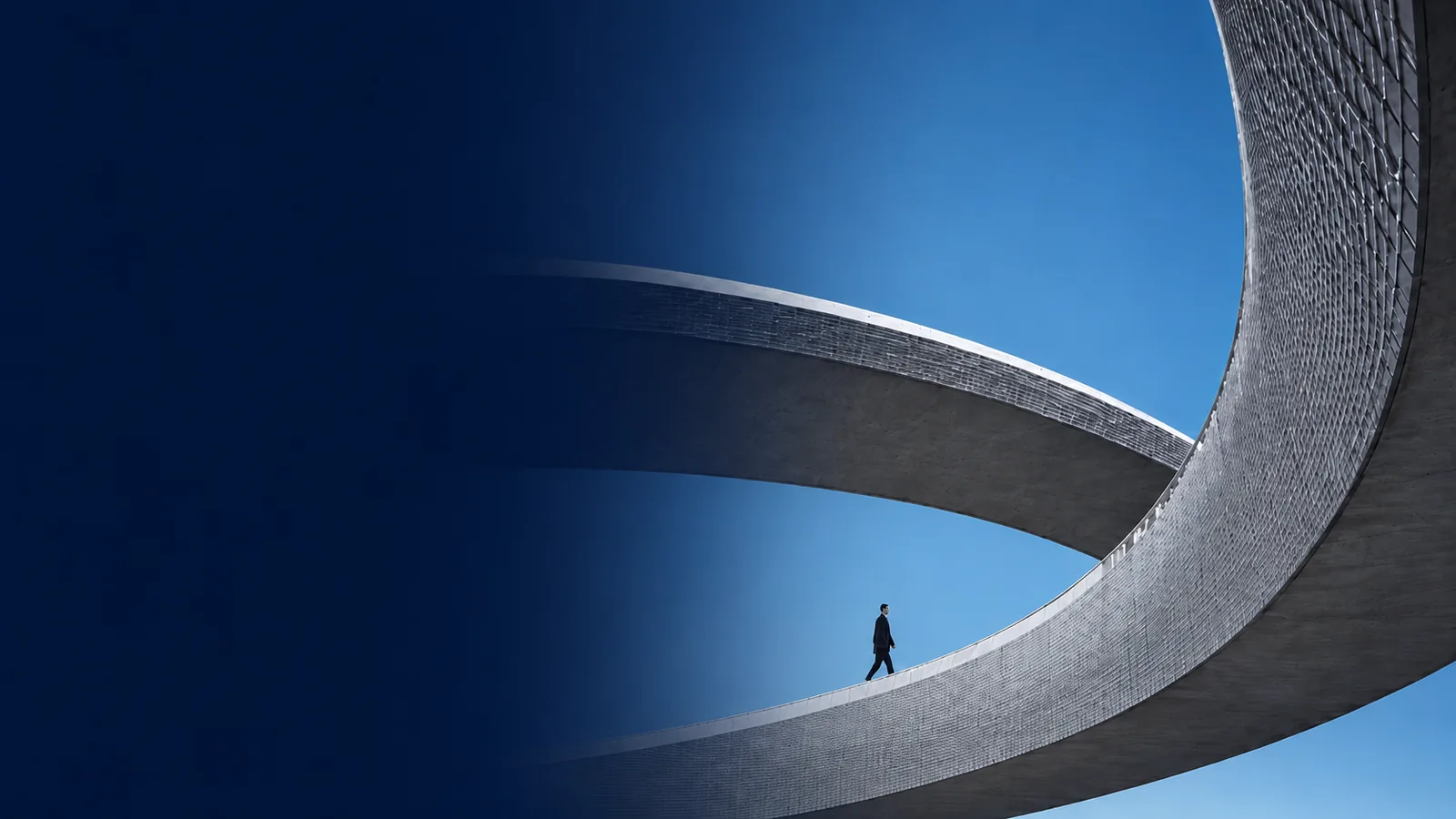 A lone figure walking through a vast curved architectural structure.